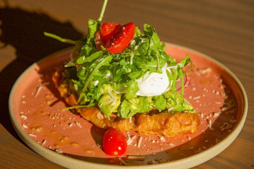 Smashed avocado on croffle, poached eggs, cherry tomatoes, parmesan, and arugula.