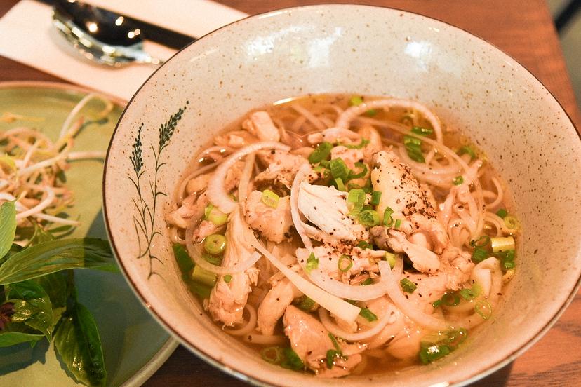 Phở with shredded chicken in a fragrant broth served with fresh herbs, bean sprouts, and lime.