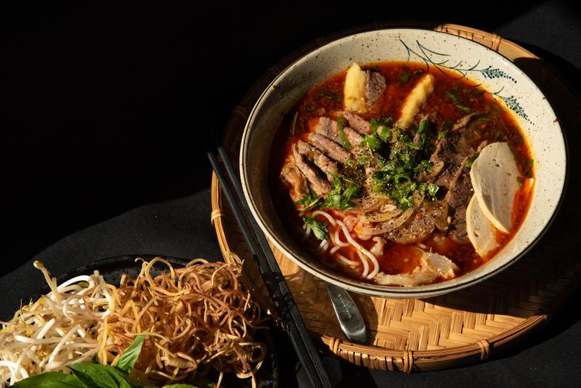 (Bún Bò Huế) Vietnamese spicy lemongrass beef noodle soup with various cuts of beef and Vietnamese sausage in a chili infusion broth served with fresh herbs, bean sprouts, and lime.